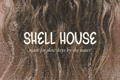Shell House beachwear logo created with Gelato Daydreams hand-drawn display font over a sandy ocean photograph for relaxed coastal branding and apparel design.